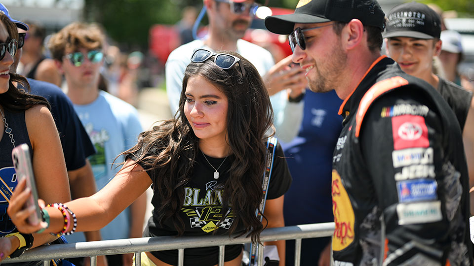 A fan takes a selfie with a NASCAR driver