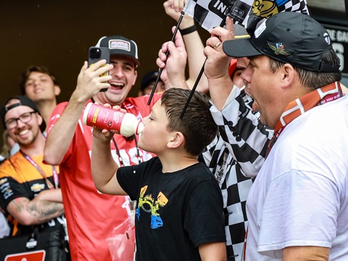 A crowd watches a child chug milk.